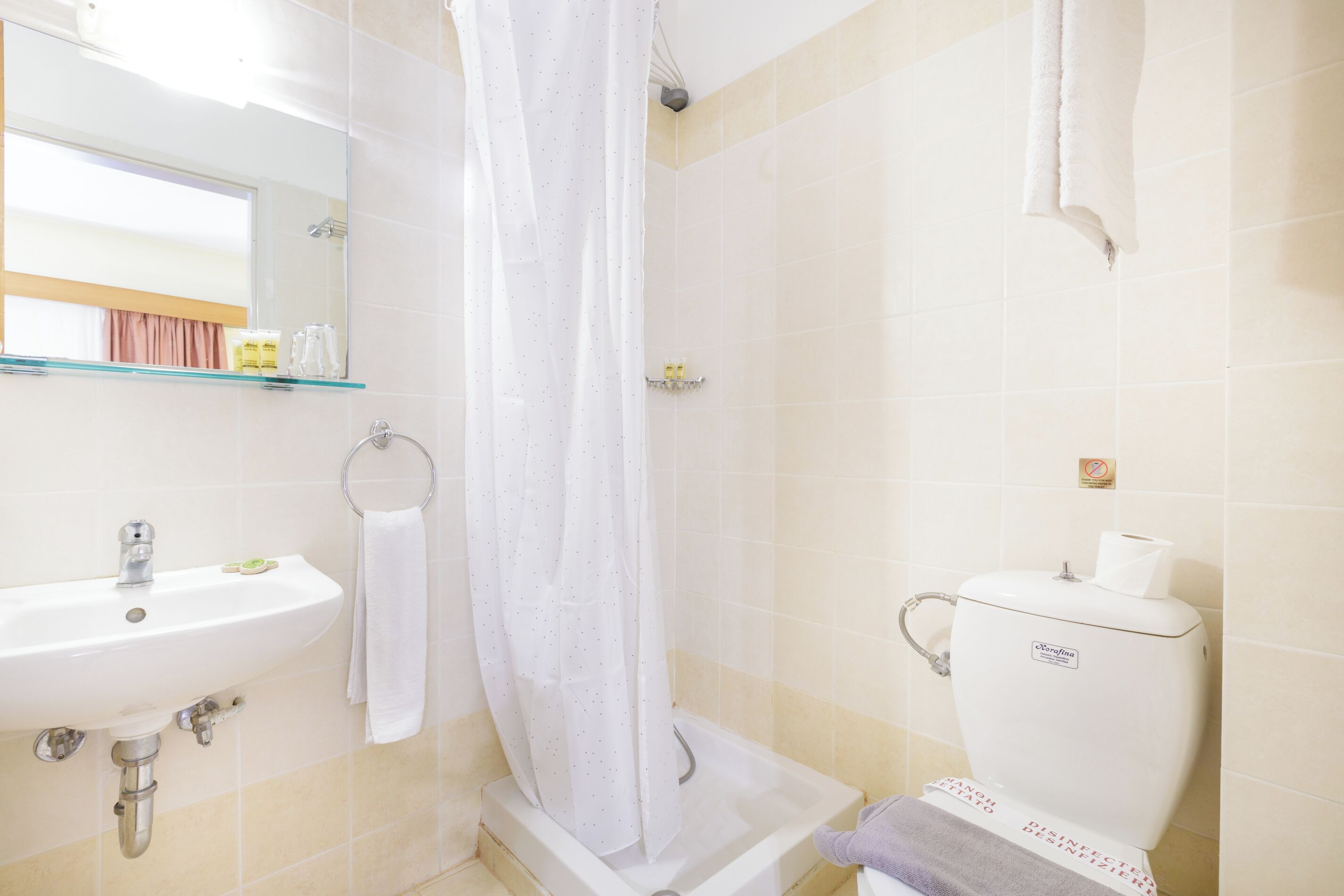 Un bagno con lavandino, WC e tenda da doccia.