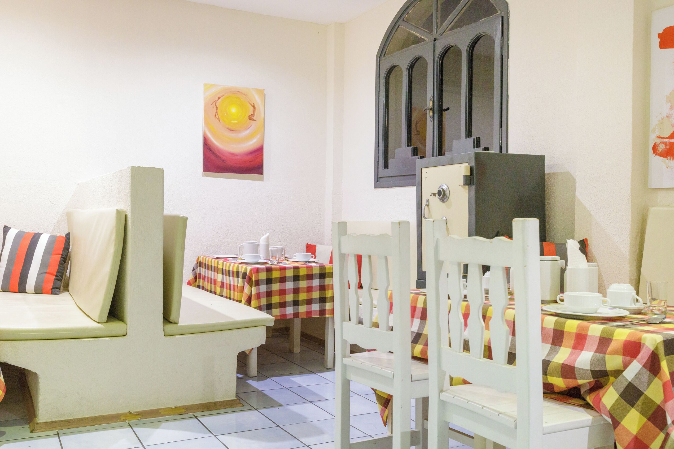 A dining area with a checkered tablecloth, a white chair, and a wall-mounted cabinet.