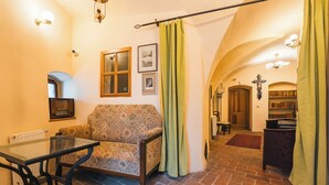 Una sala acogedora con un sofá estampado, una mesa de vidrio y un suelo de ladrillo.