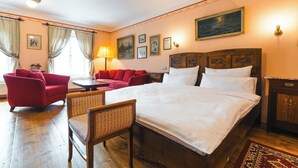 Una habitación de hotel con una cama grande, un sofá rojo, una silla de madera y una mesita.