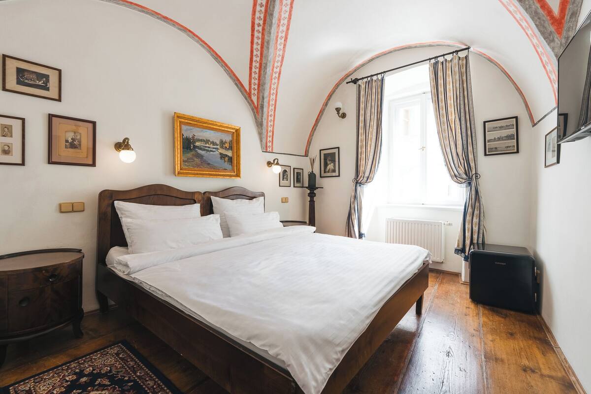 A bedroom with a wooden bed, a nightstand, a radiator, and a suitcase.