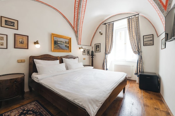 A bedroom with a wooden bed, a nightstand, a radiator, and a suitcase.