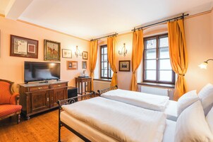 Una habitación de hotel con dos camas, un televisor, un armario de madera y una silla.