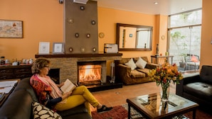 A cozy living room with a fireplace, comfortable seating, and a large window.