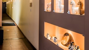 A hallway with a wall displaying various decorative items and a website address.