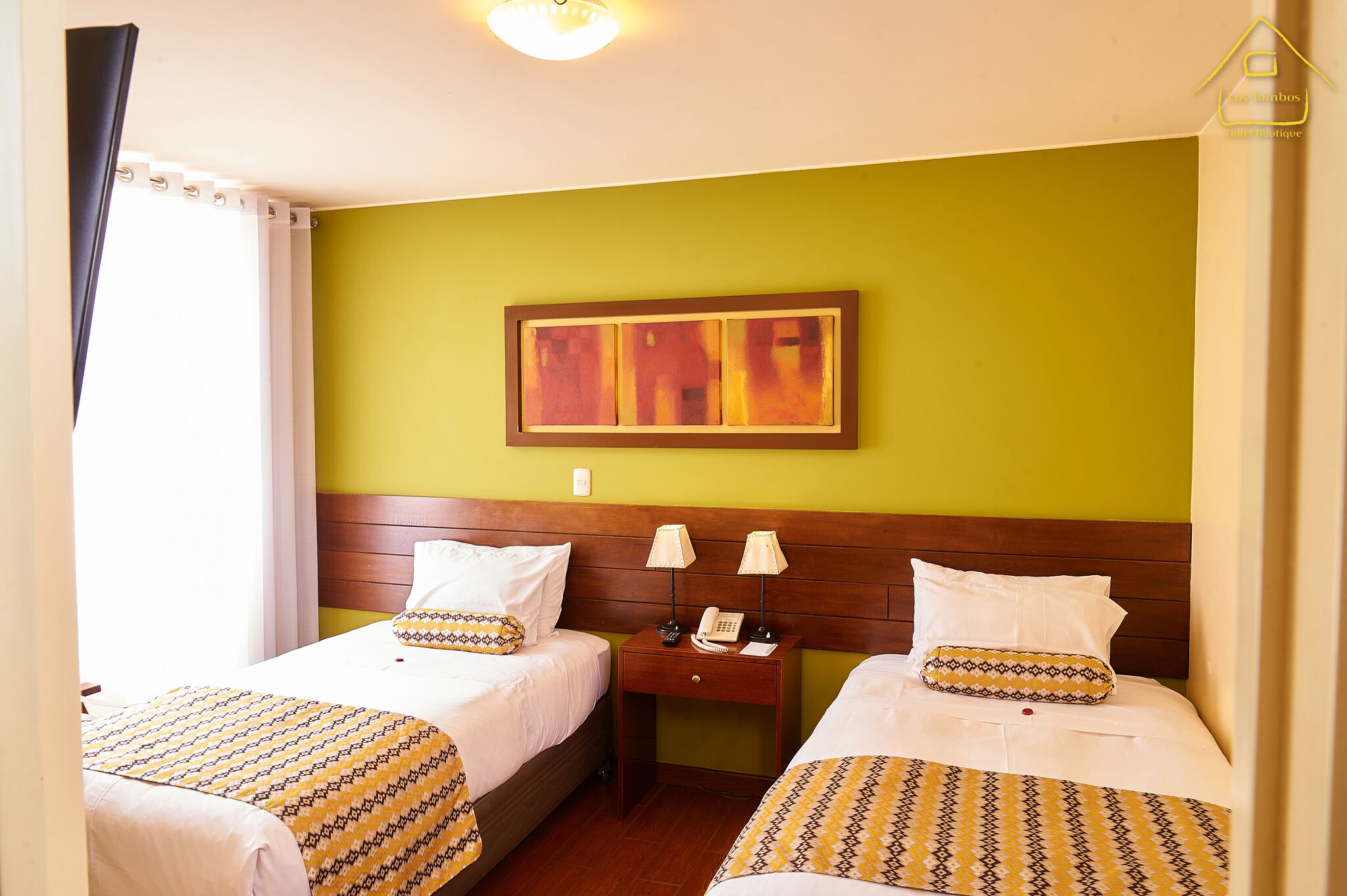 A hotel room with two beds, a nightstand with lamps, and a painting on the wall.