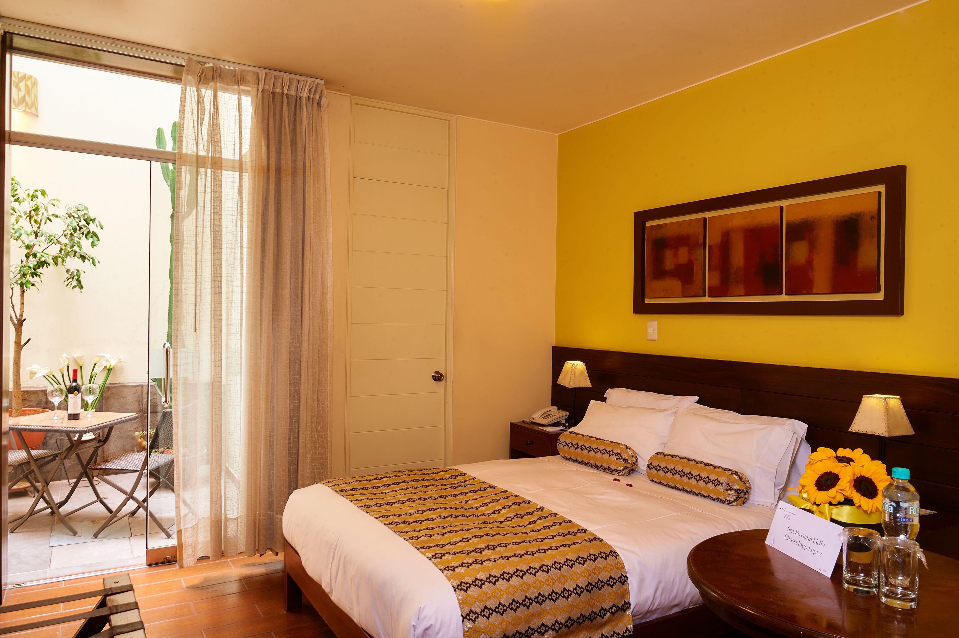 Une chambre d’hôtel avec un lit, une table de chevet, une table avec des chaises et une vue sur l’extérieur.