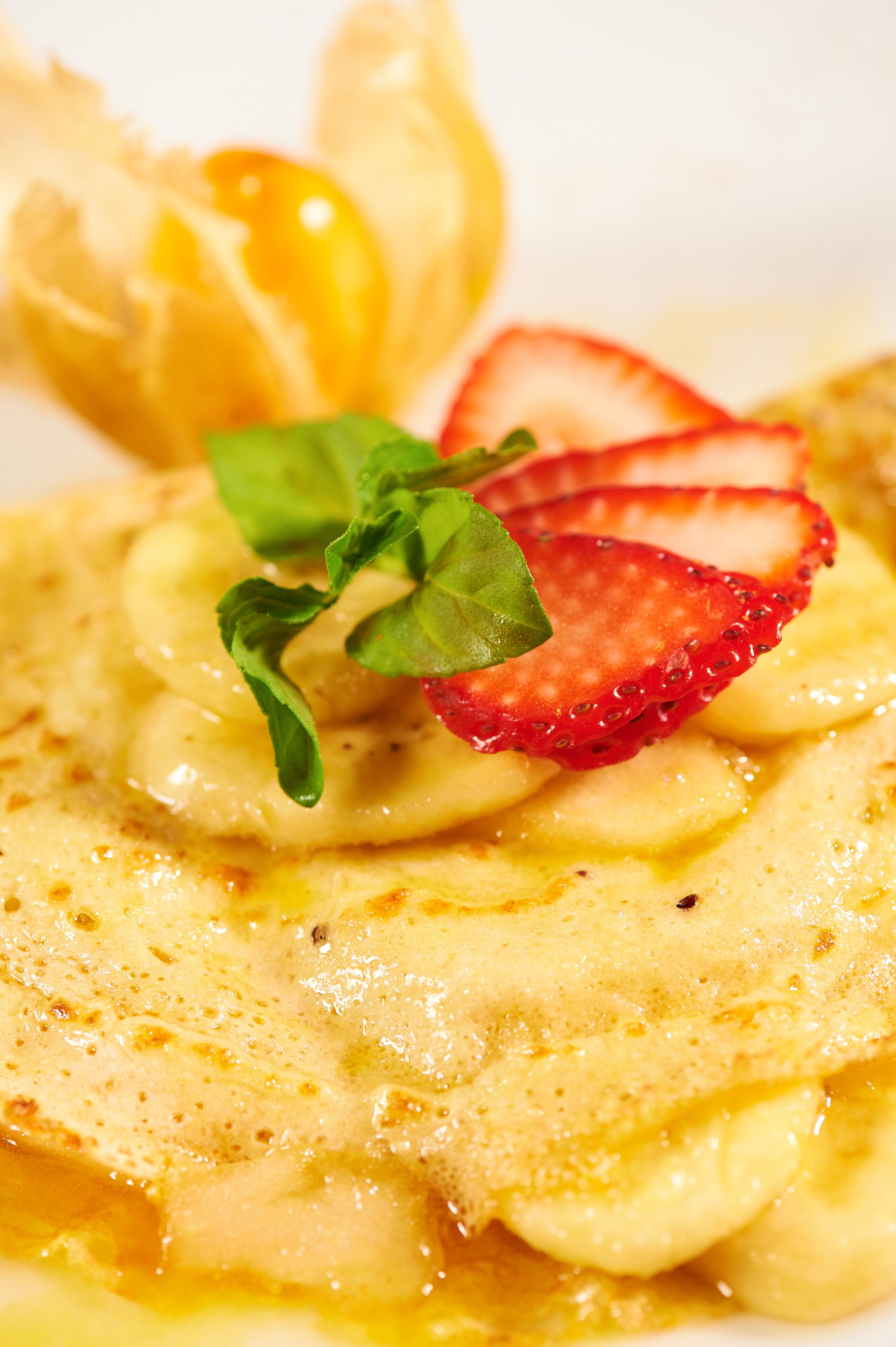 A dessert with banana slices, strawberries, and mint leaves.