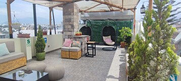 A rooftop terrace with a seating area, hanging chairs, and potted plants.