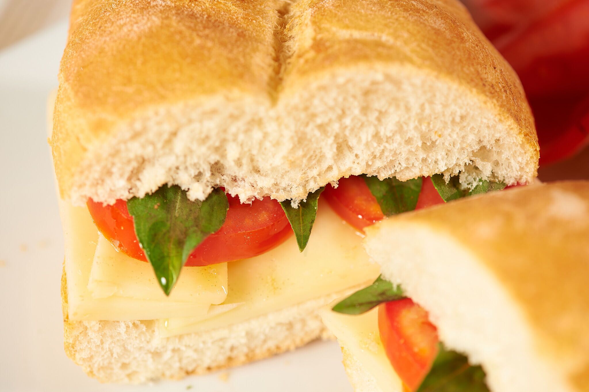 Un sandwich dans lequel on peut voir clairement les ingrédients, comme les tomates, le fromage et la laitue.