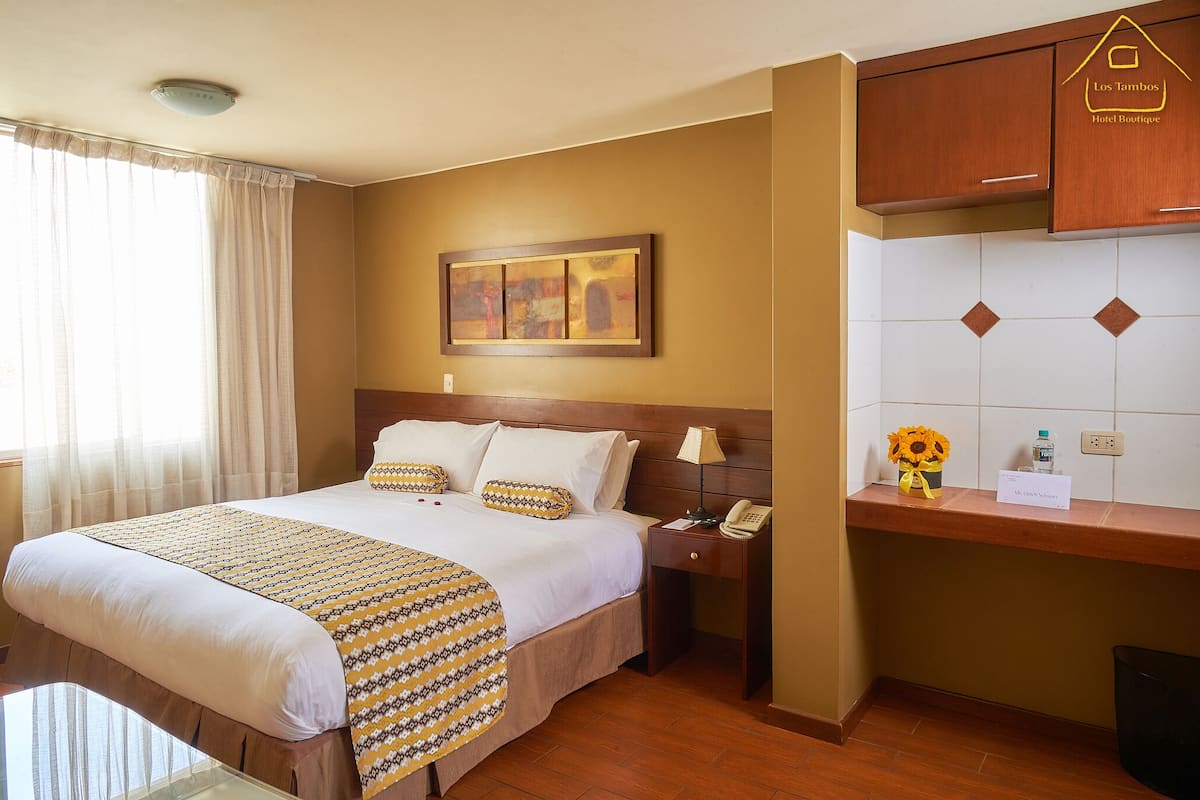 A hotel room with a bed, bedside table, and a small desk with a telephone.