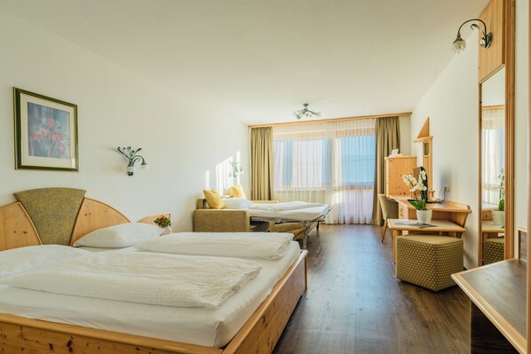 Una habitación de hotel con dos camas, un escritorio, una silla, un espejo y una ventana con cortinas.