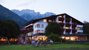 A multi-story hotel with balconies, surrounded by mountains.