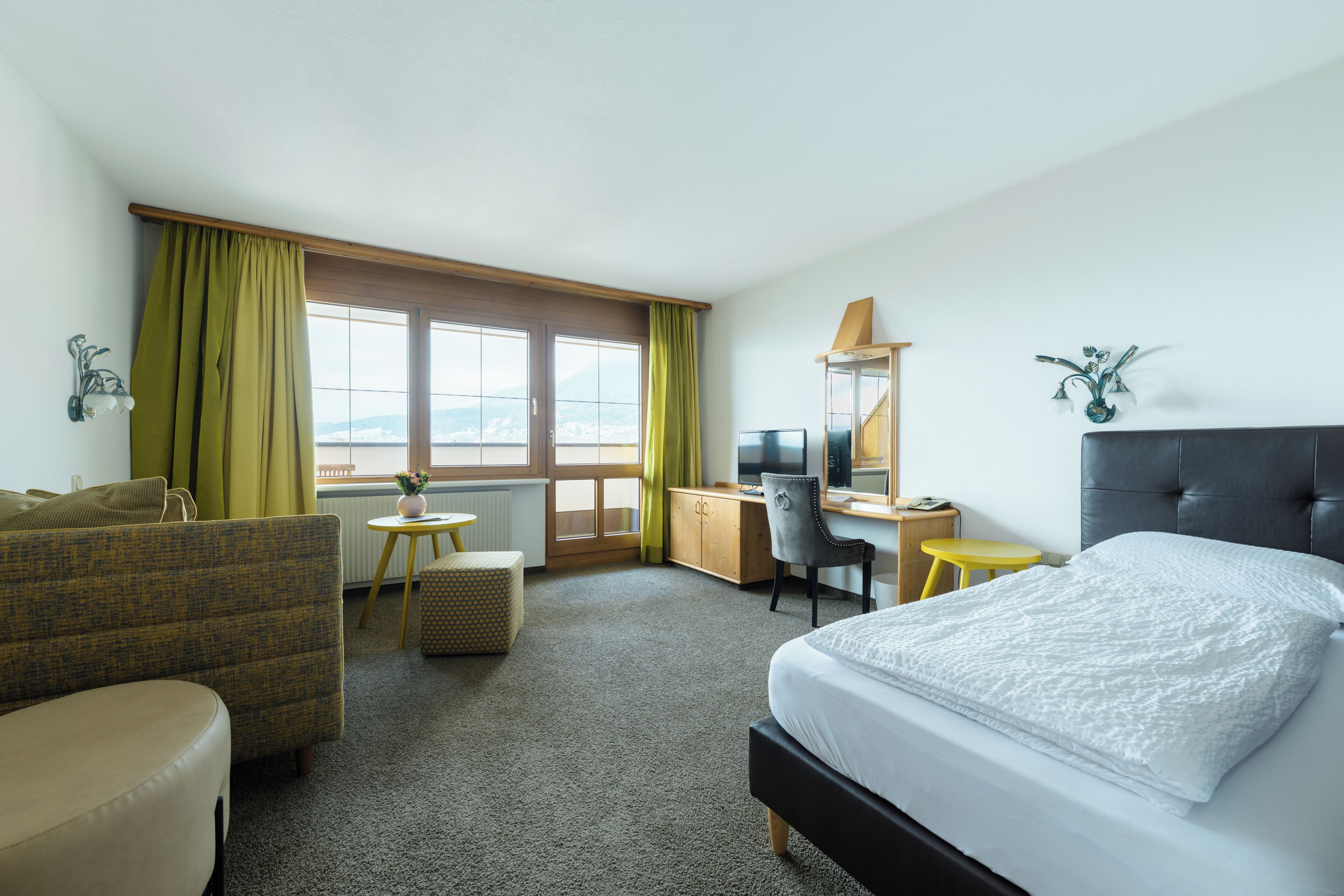 Une chambre d’hôtel équipée d’un lit, d’un bureau, d’une chaise, d’un canapé et offrant une vue sur l’extérieur.