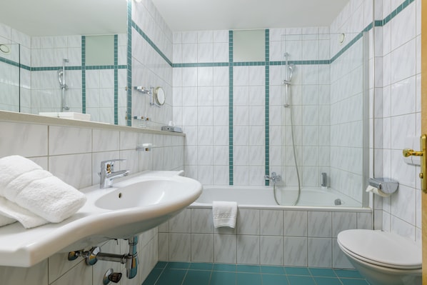 A bathroom with a sink, mirror, bathtub, and toilet.