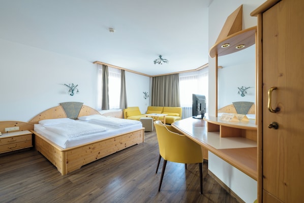 A hotel room with a wooden bed, a desk, a chair, a television, and a wardrobe. - Landgasthof Bogner (Absam)
