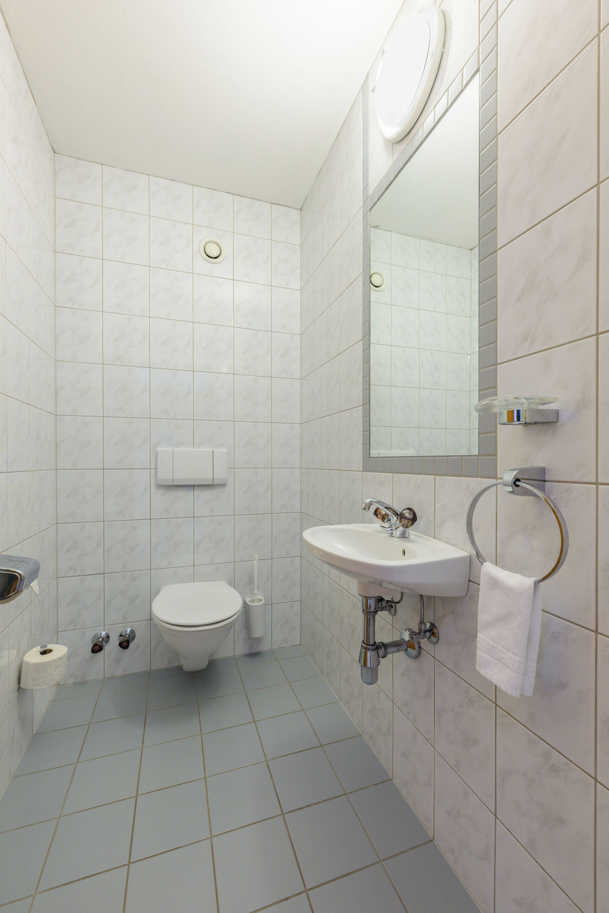 Et moderne badeværelse med toilet, vask og spejl.