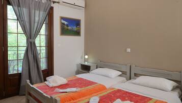 Una camera d'albergo con due letti, un comodino con una lampada, un quadro appeso al muro e una finestra con tende.