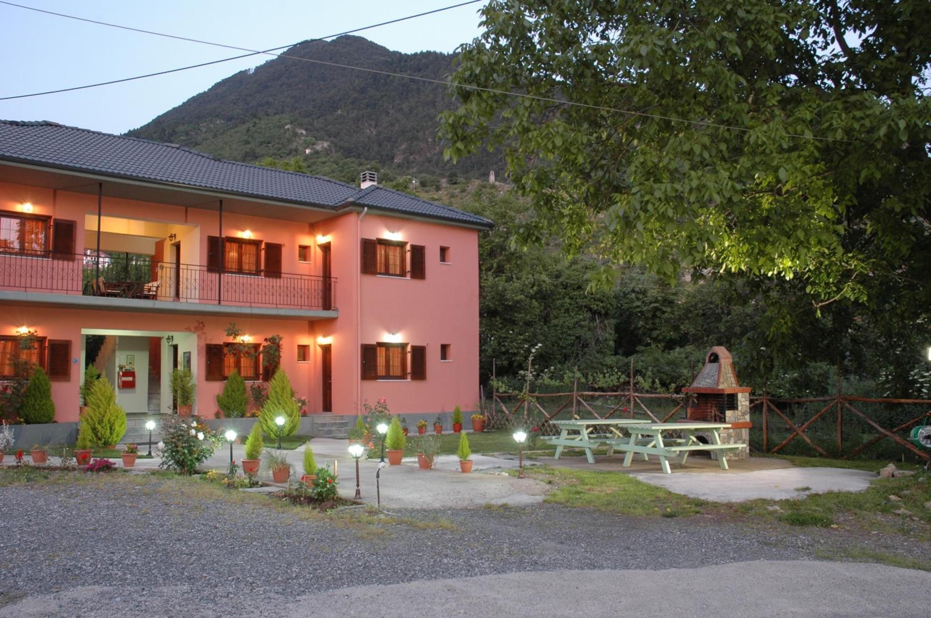 A two-story building with a balcony, a patio area with a table and chairs, and a small outdoor oven.