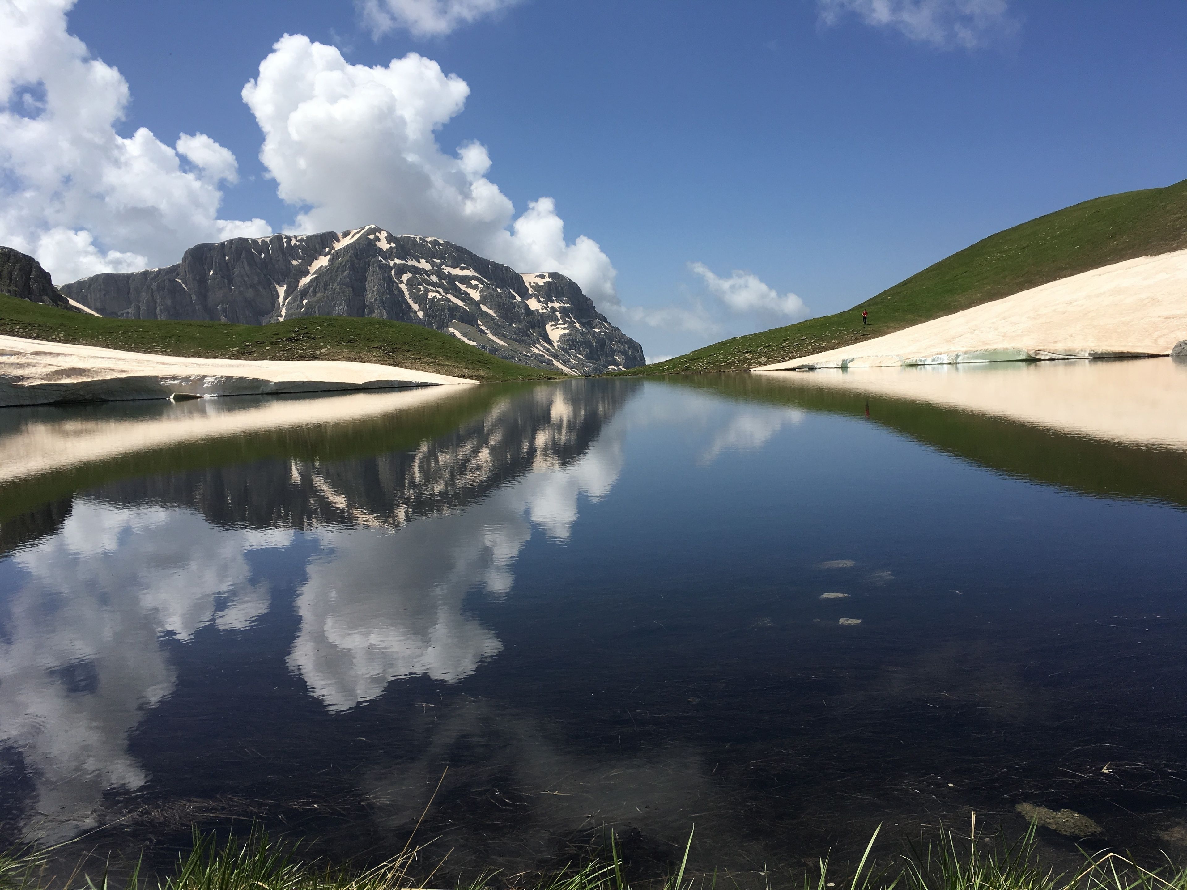 A calm lake reflecting mountains and a clear sky.