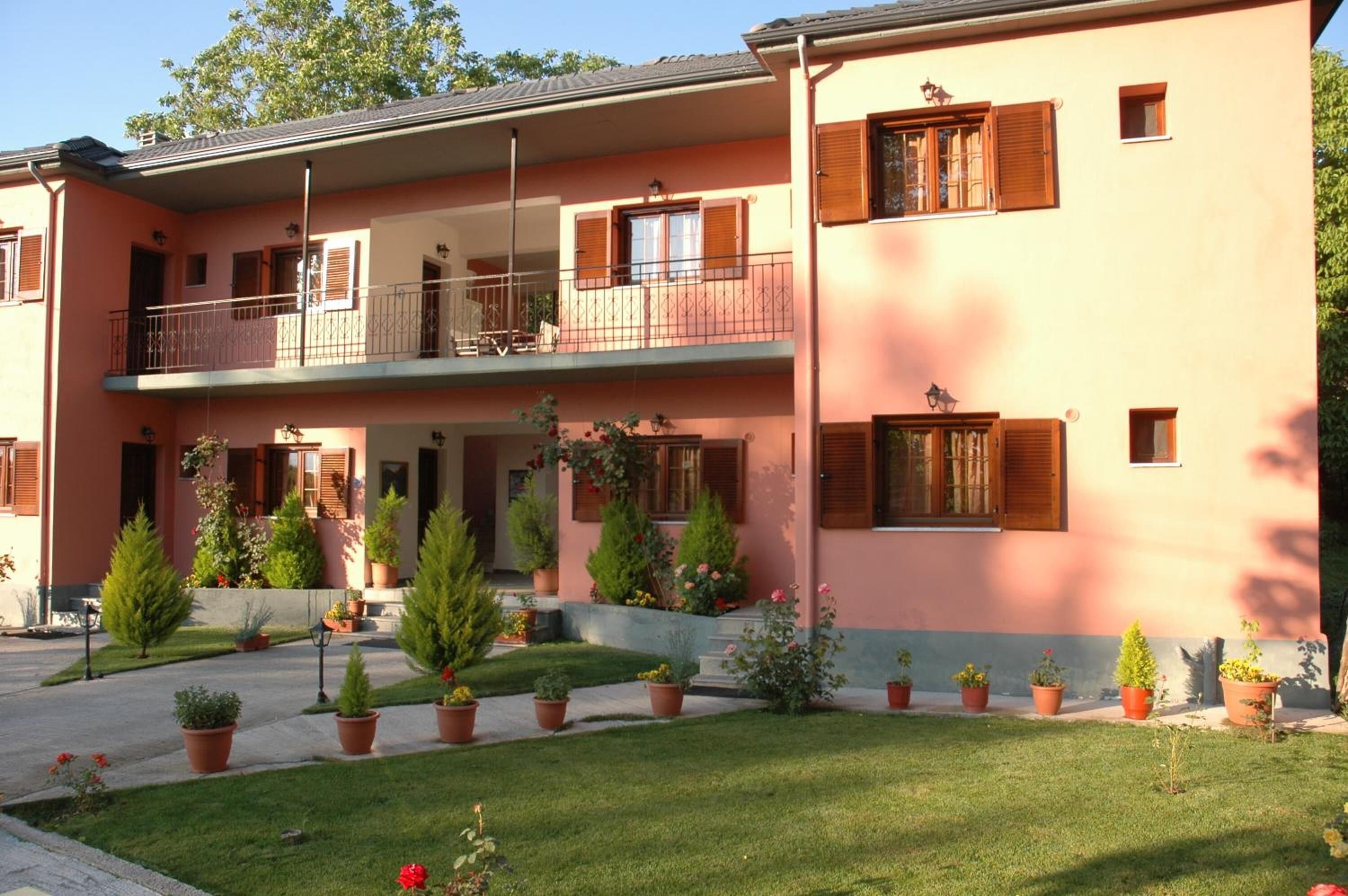A two-story building with a balcony on the upper floor, potted plants, and a well-maintained lawn.