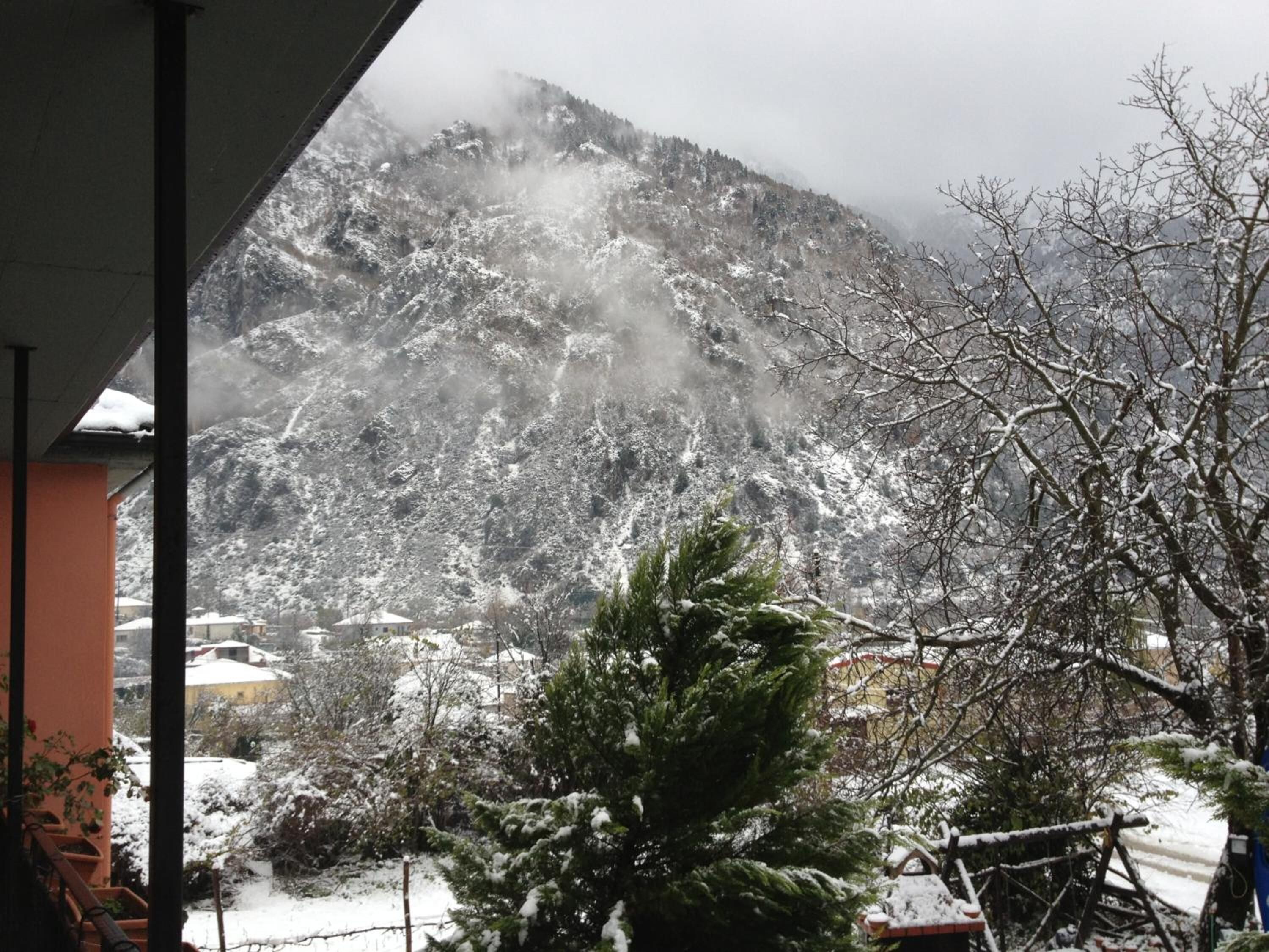 A mountain view with snow-covered trees and a building in the foreground.