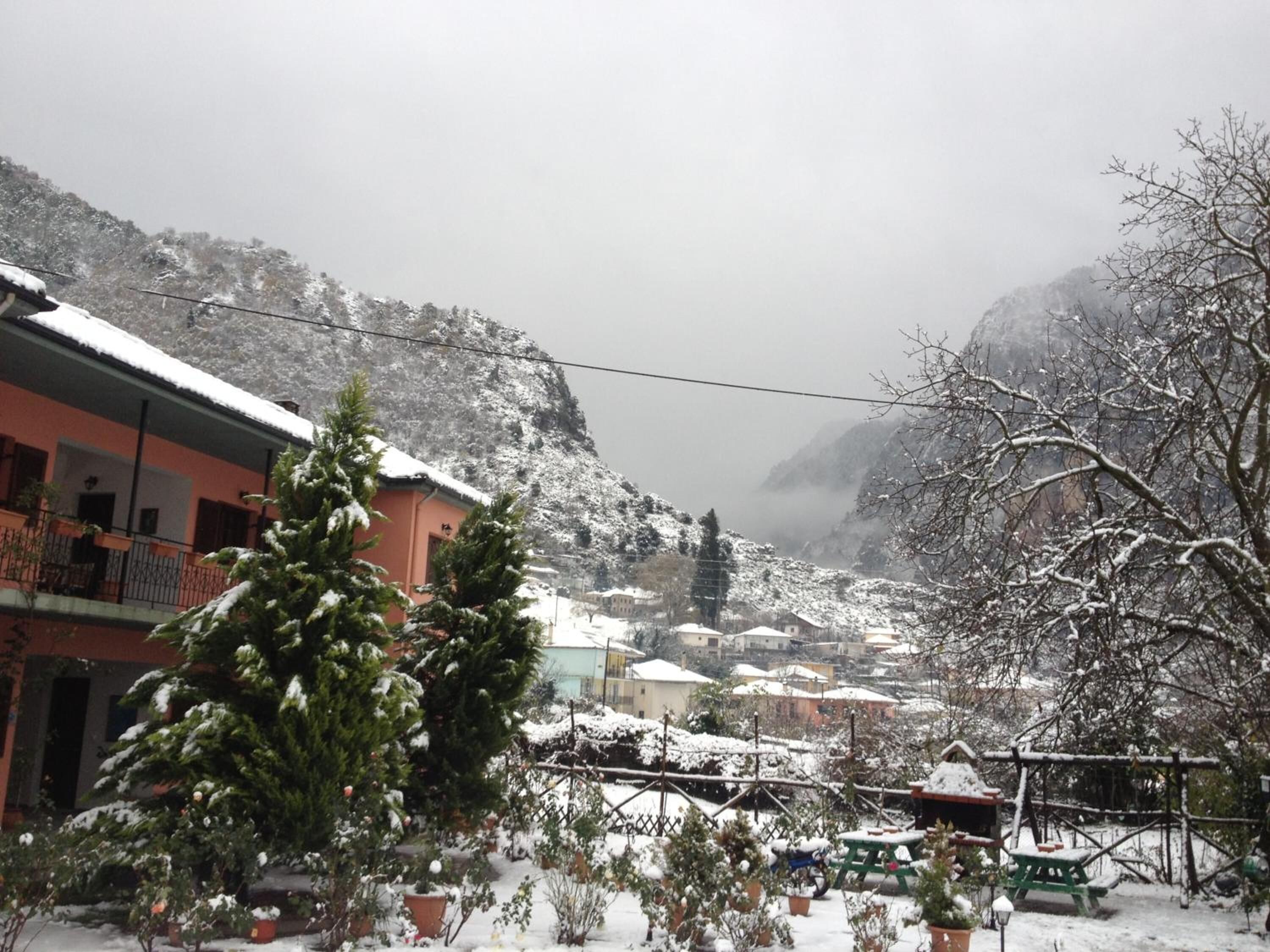 A snow-covered village with buildings, a mountain backdrop, and a clear sky.