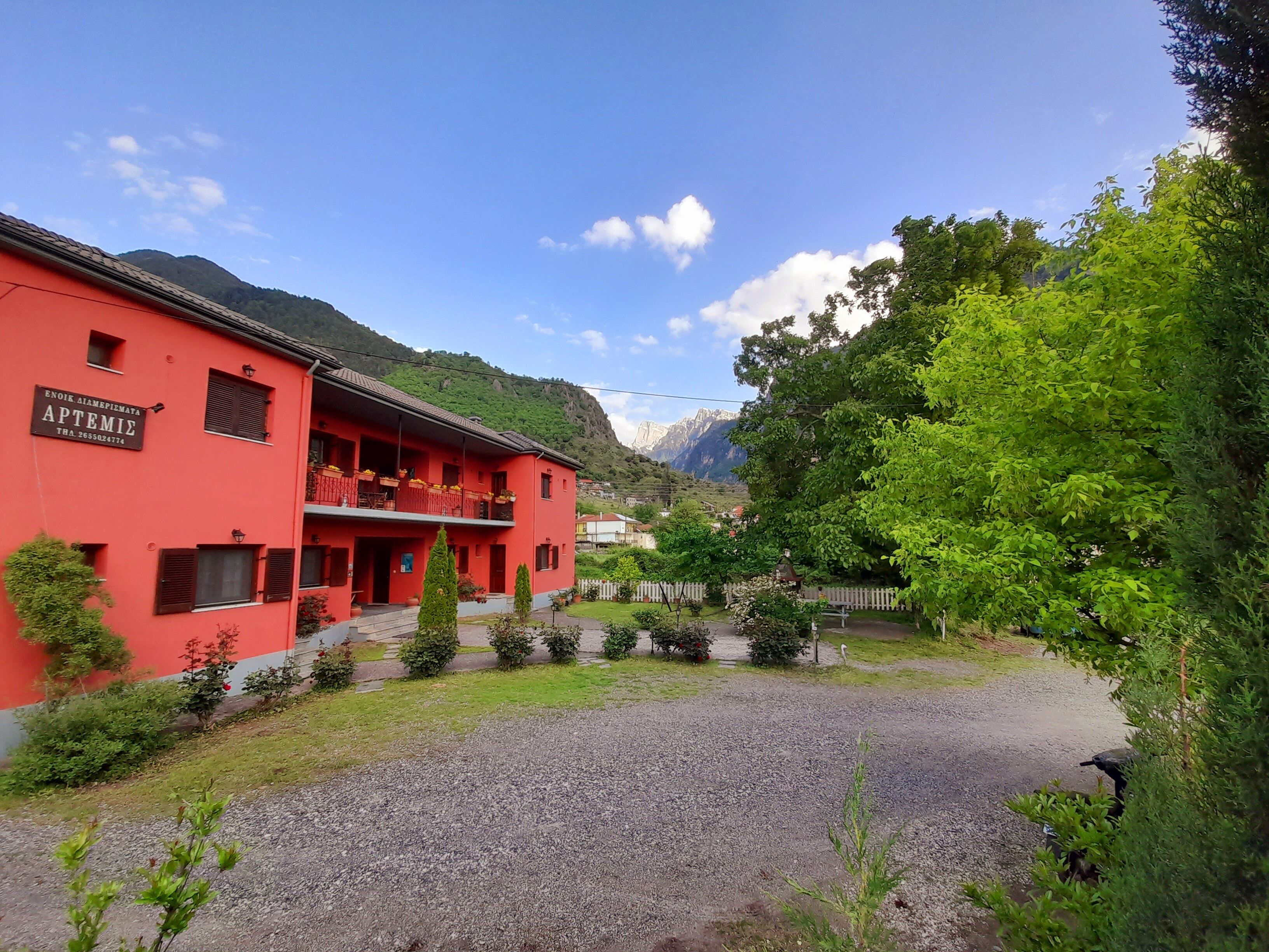 A red building with a sign reading "APTEMIE" and a mountain in the background.