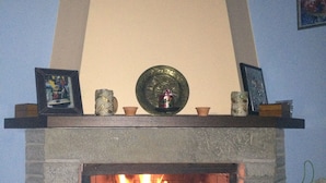 Una chimenea con repisa adornada con varios objetos, incluyendo marcos con fotografías y velas.