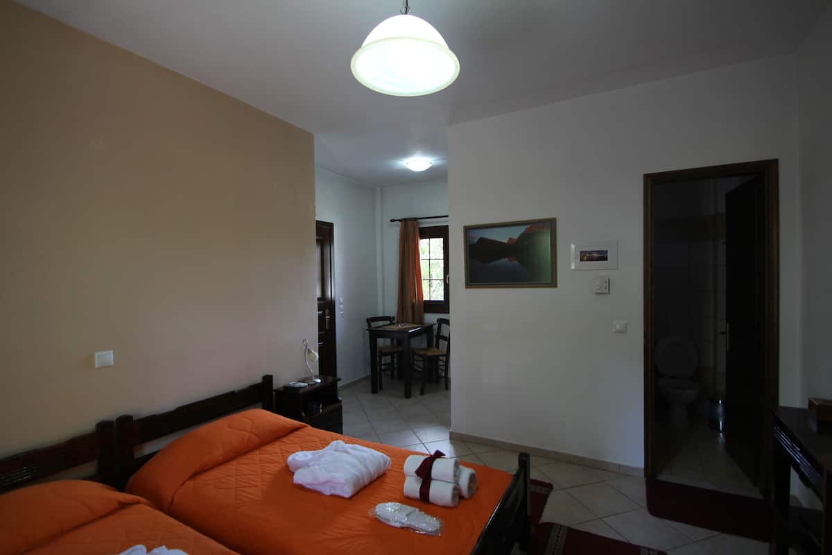 Habitación de hotel con dos camas, un comedor y un baño.