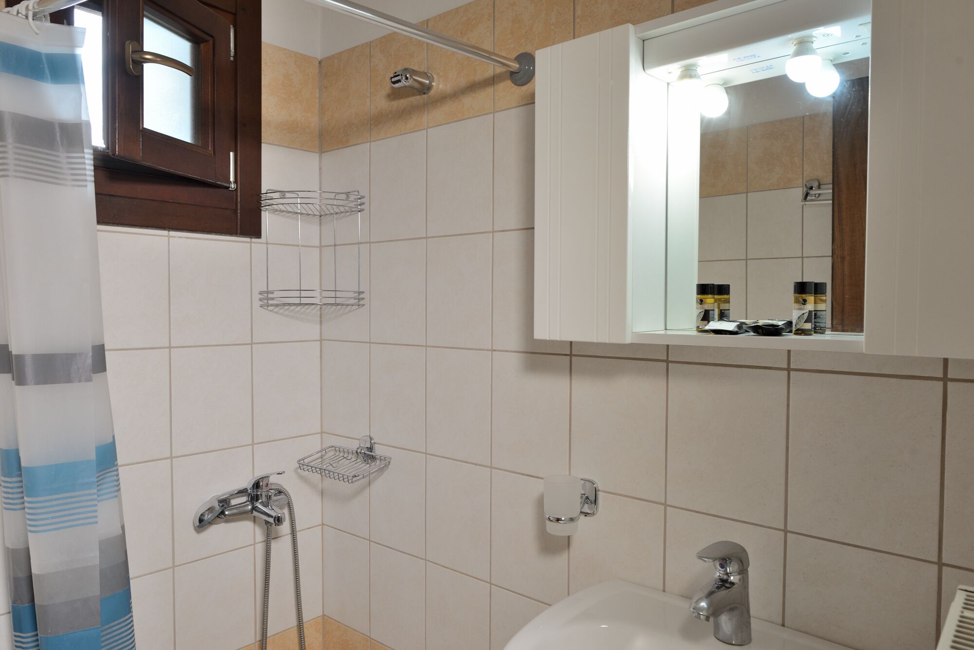 Ein Badezimmer mit Dusche, Waschbecken, Spiegel und Handtuchhalter.