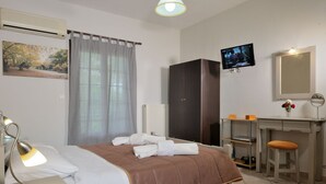 Habitación de hotel con cama, escritorio con computadora, televisión, armario y zona de baño.