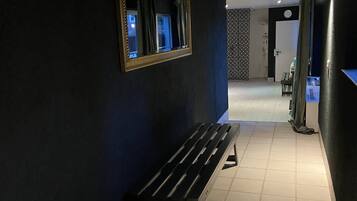 Un pasillo con un banco, una cesta y un espejo en la pared.