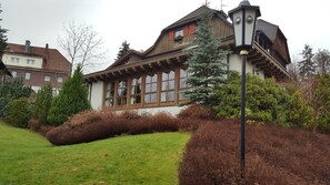 A traditional chalet-style building with a sloped roof, wooden beams, and large windows. - Landhaus Foresta (Braunlage)