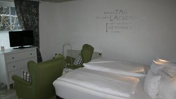 Una habitación de hotel con una cama, dos sillas, un televisor y una pared con una cita motivacional.
