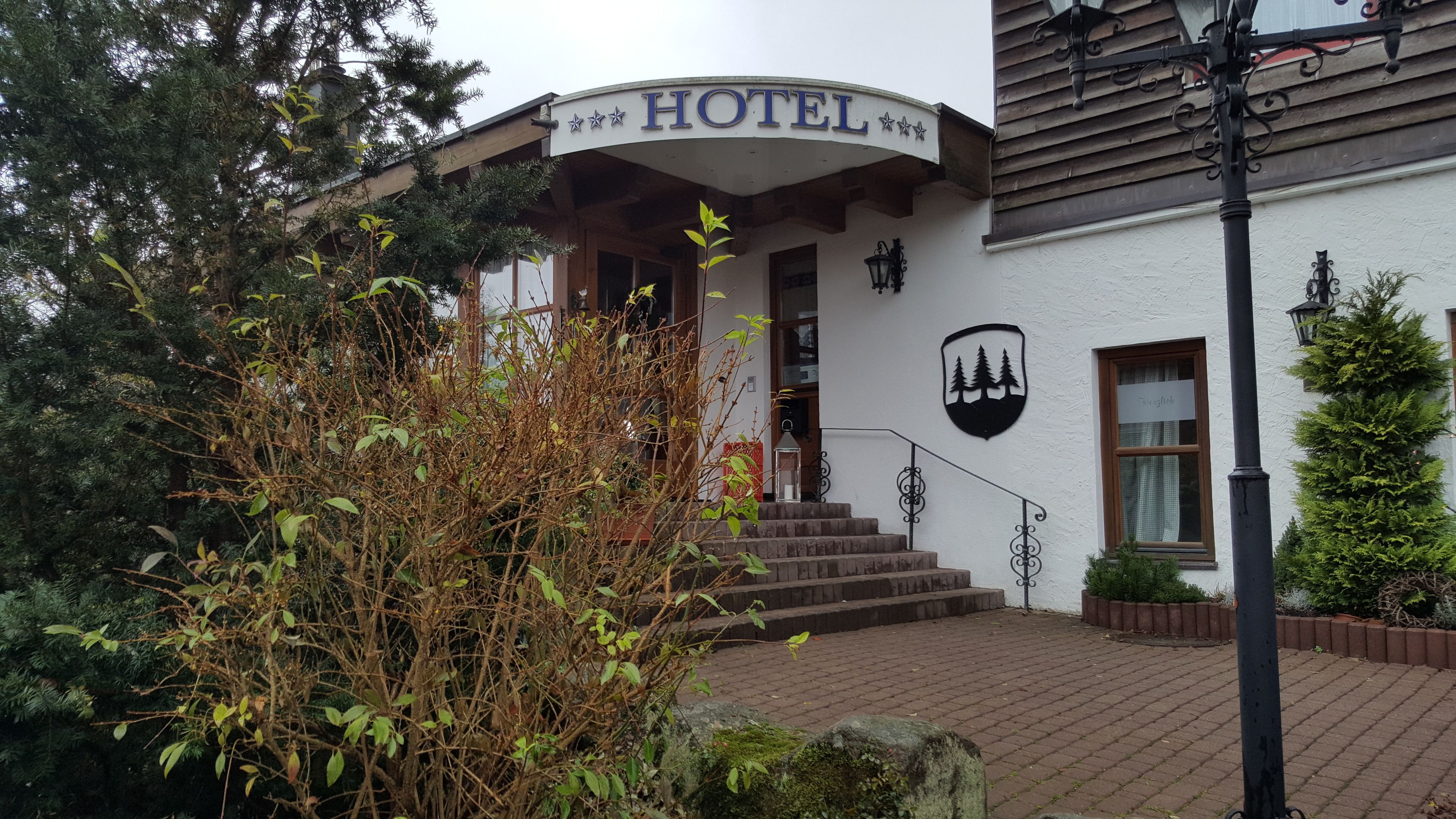Ein Hotel Eingang mit Schild, Stufen und einem Logo an der Wand.