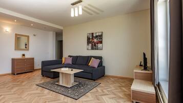 A modern living room with a sofa, a coffee table, a mirror, and a painting on the wall.