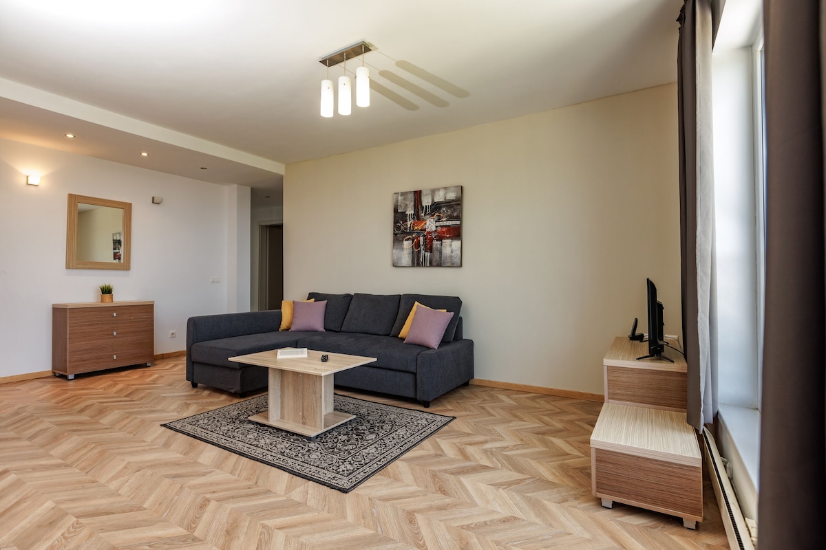 A modern living room with a sofa, a coffee table, a mirror, and a painting on the wall.