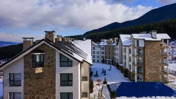 A multi-story building with a stone facade, multiple balconies, and a snow-covered roof.