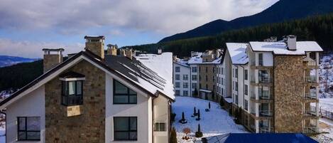 A multi-story building with a stone facade, multiple balconies, and a snow-covered roof.