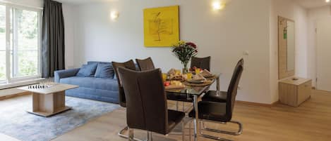 Een moderne woonkamer met een bank, eettafel, stoelen en een tafelvoetbaltafel.