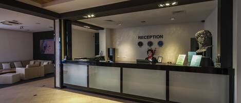 Un área de recepción con diseño moderno, que incluye un mostrador de recepción, un reloj de pared y un mostrador de atención al cliente.