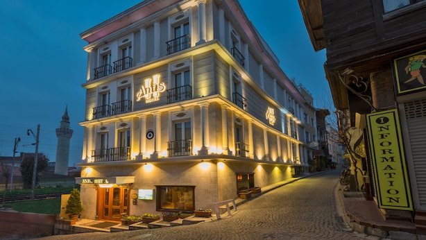 A historic hotel with a classic facade, multiple balconies, and a well-lit entrance.