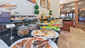 A buffet with various food items, including fruits, vegetables, and pastries, arranged on a marble counter.
