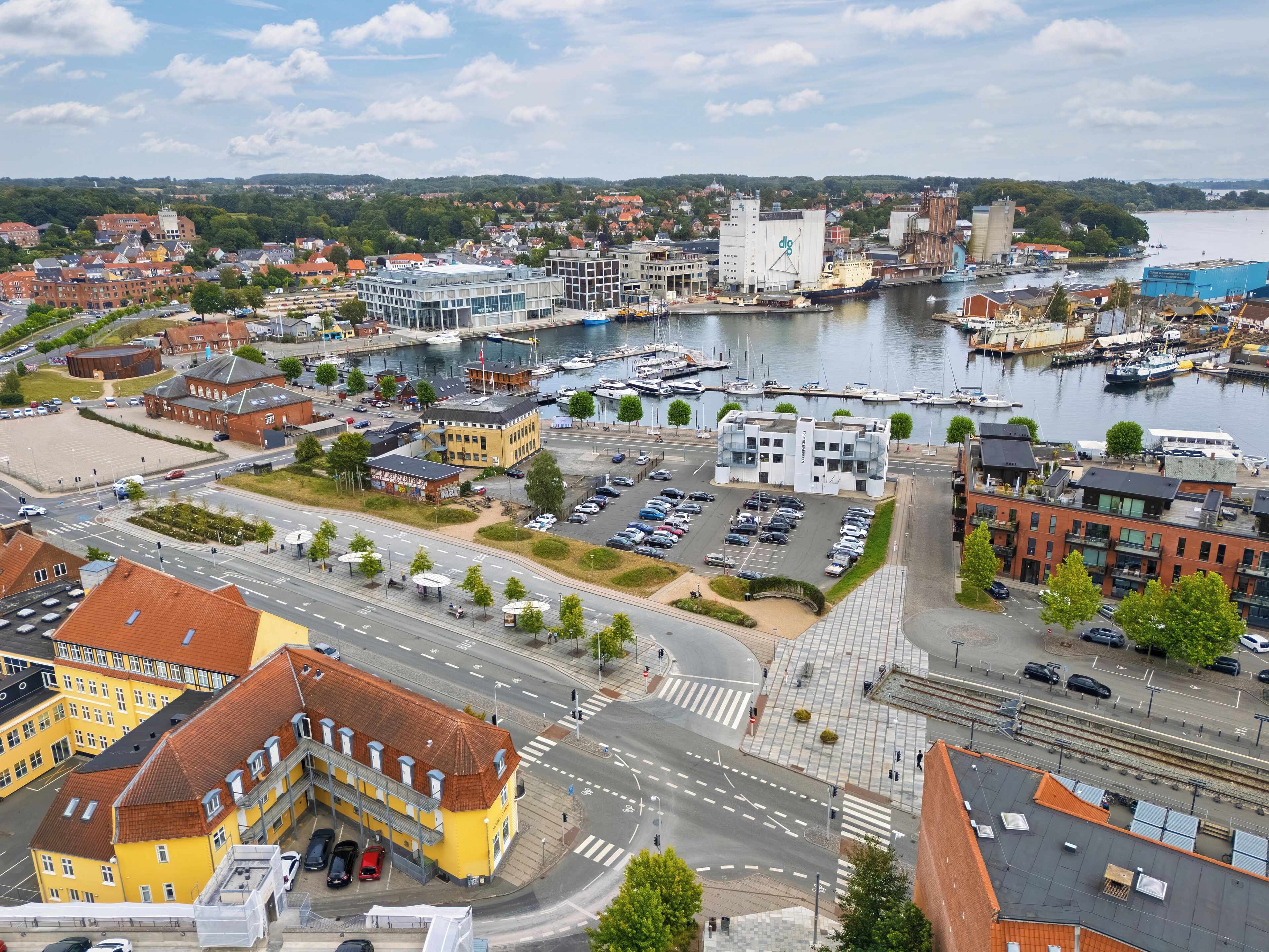 Un paisaje urbano costero con un puerto deportivo, edificios modernos y una iglesia histórica.