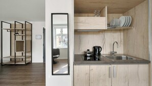Una cocina moderna con armarios de madera, un lavamanos integrado y una cafetera.