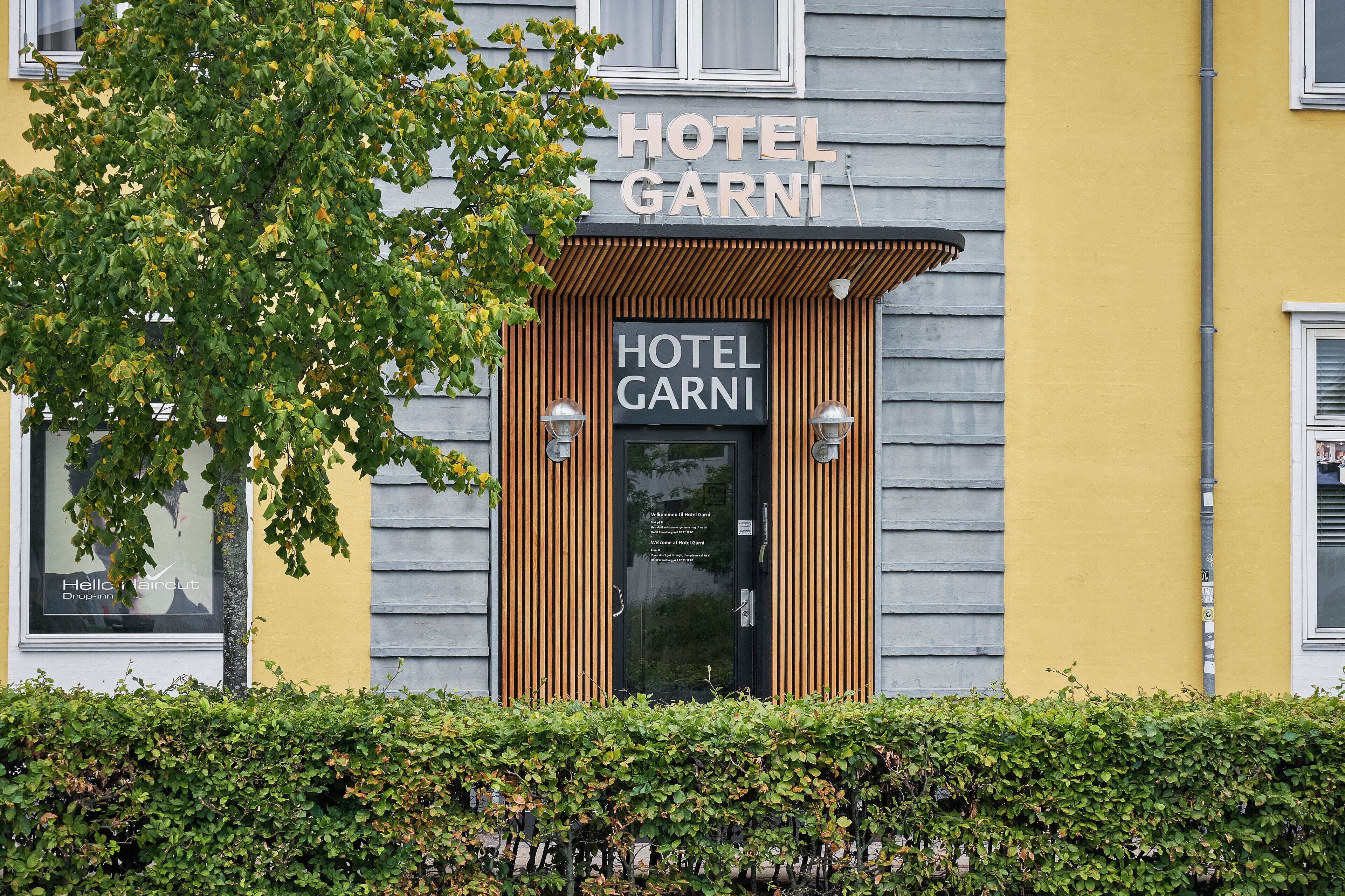 A hotel entrance with a sign reading 'HOTEL GARNI' and a wooden facade.
