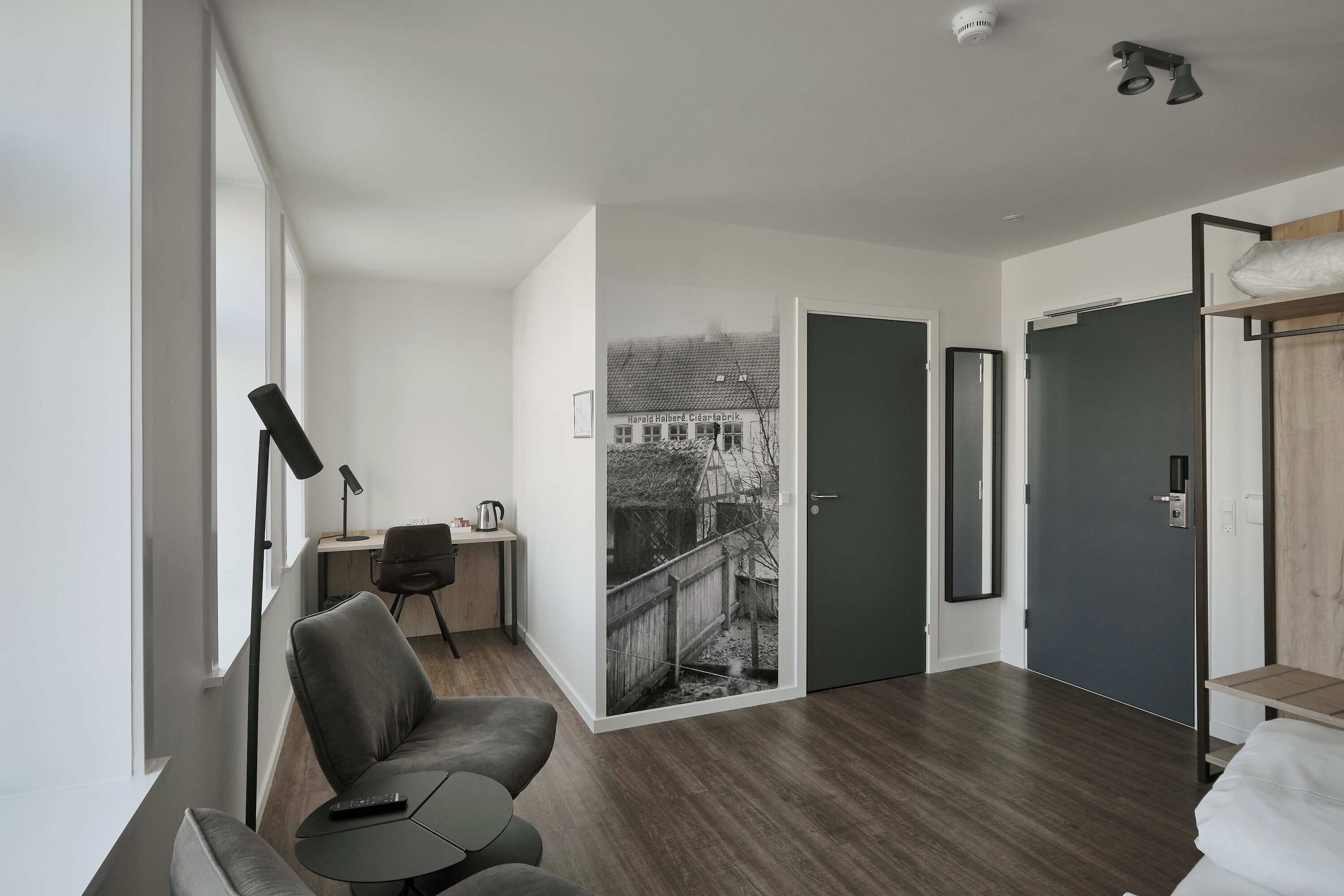 Een moderne hotelkamer met een groot raam, een bureau met stoel, een bank en een bed.