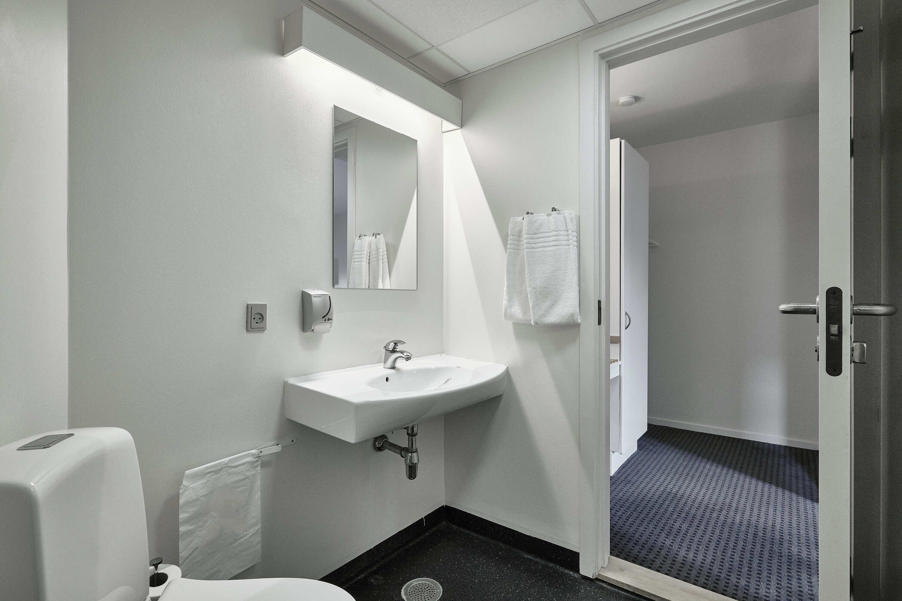 A bathroom with a white sink, a mirror, and a towel rack.