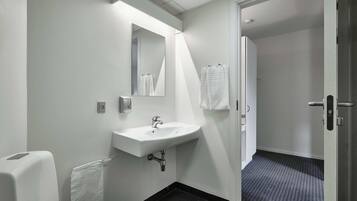 A bathroom with a white sink, a mirror, and a towel rack.